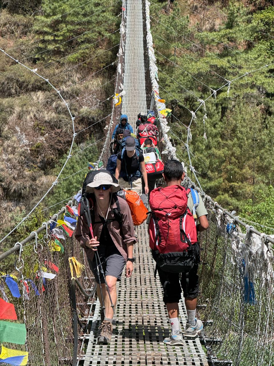 Trekkers crossing a suspension bridge in the Himalayas